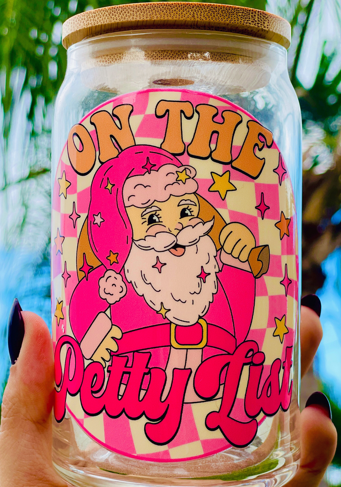 A 16 oz glass cup featuring a festive pink Santa design with the phrase 