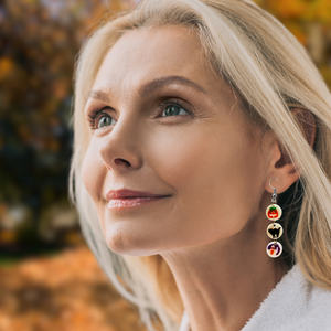 Earrings featuring mini replicas of Pillsbury Halloween sugar cookies, including jack-o'-lanterns, black cats, and ghosts, dangling from hooks against an orange background. Perfect for Halloween nostalgia and fun fall fashion.