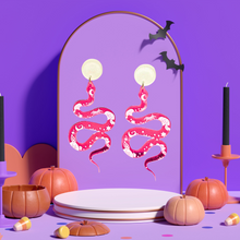 Load image into Gallery viewer, Pink earrings with a mystical snake design and celestial markings, perfect for adding a magical touch to your Halloween style
