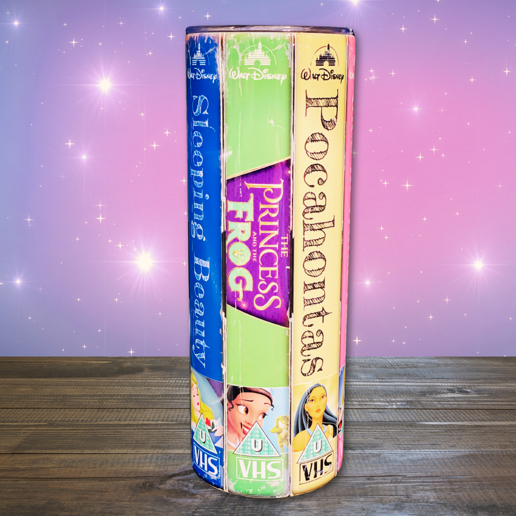 A 20 oz stainless steel insulated tumbler featuring a vibrant design with vintage Disney princess VHS covers, including Sleeping Beauty, The Princess and the Frog, and Pocahontas. Comes with a clear lid, metal straw, and straw cleaner, perfect for hot and cold drinks.