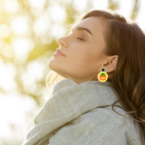 A model wearing a fall scarf and pumpkin sugar cookie earrings