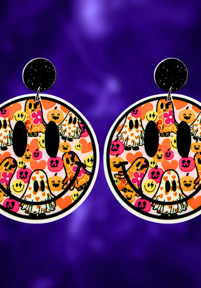 A purple background with earrings featuring a smiley face filled with colorful ghosts and flowers, perfect for a fun and lighthearted Halloween look