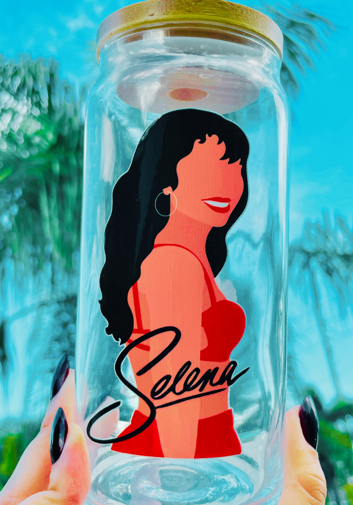 A 20 oz glass cup featuring iconic Selena Quintanilla designs with a bamboo lid and reusable glass straw. Perfect for fans of the late Tejano music legend.