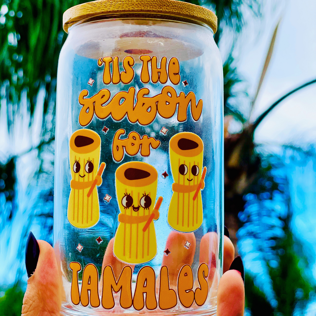 A 16 oz glass cup featuring a cute tamale-themed UVDTF wrap with the phrase “’Tis the Season for Tamales.” Includes a bamboo lid and reusable glass straw, perfect for cold drinks. BPA-free and handwash only.