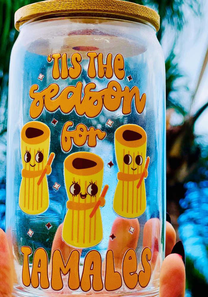 A 16 oz glass cup featuring a cute tamale-themed UVDTF wrap with the phrase “’Tis the Season for Tamales.” Includes a bamboo lid and reusable glass straw, perfect for cold drinks. BPA-free and handwash only.