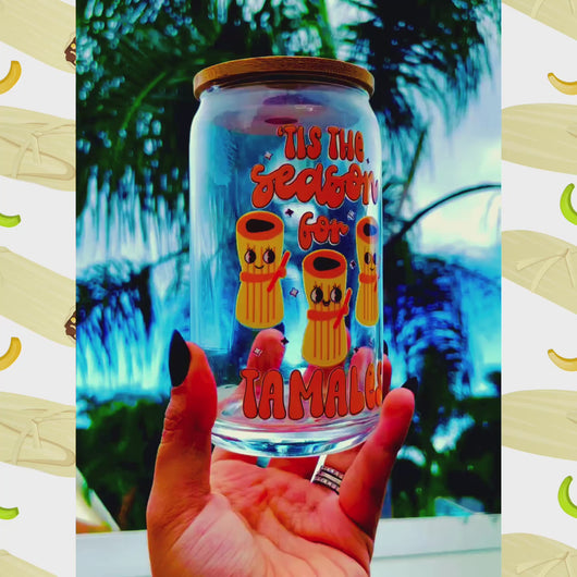 A 16 oz glass cup featuring a cute tamale-themed UVDTF wrap with the phrase “’Tis the Season for Tamales.” Includes a bamboo lid and reusable glass straw, perfect for cold drinks. BPA-free and handwash only.