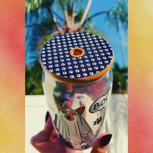 A 16 oz glass cup with a Halloween design of dogs dressed as ghosts, featuring “boo” speech bubbles, paw prints, a bamboo lid, and a reusable glass straw.