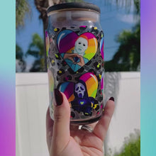 Load and play video in Gallery viewer, A 16 oz glass cup with a colorful design of rainbow hearts featuring horror movie icons like Michael Myers and Freddy Krueger, paired with a rainbow leopard bamboo lid and reusable glass straw.
