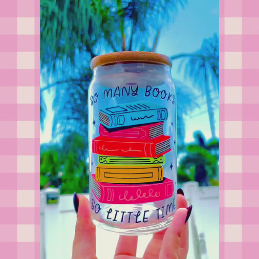 A 16oz BPA-free glass cup with a UVDTF wrap featuring colorful stacked books and the phrase "So Many Books, So Little Time." Includes a bamboo lid and reusable glass straw, perfect for book lovers and cold drinks.