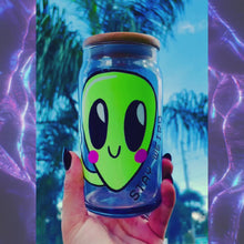 Load and play video in Gallery viewer, A 20 oz glass cup featuring a cute green alien design with the words &quot;Stay Weird,&quot; paired with a bamboo lid and reusable glass straw. Perfect for quirky drinkware lovers and iced coffee enthusiasts.
