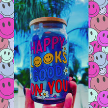 Load and play video in Gallery viewer, A 16oz BPA-free glass cup featuring a retro-inspired UVDTF design with smiley faces, daisies, and the phrase &quot;Happy Looks Good on You,&quot; complete with a bamboo lid and reusable glass straw.
