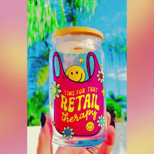 Load and play video in Gallery viewer, A vibrant 20 oz BPA-free glass cup with a bold design reading “Time for that Retail Therapy,” featuring a pink tote bag, smiley face, daisies, and stars. Comes with a bamboo lid and reusable glass straw.
